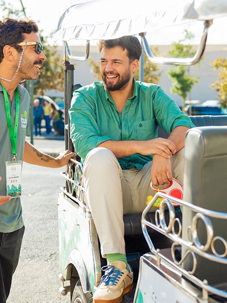Tourist guide talking with tourists on a tuk tuk in Lisbon.