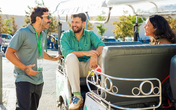 Tourist guide talking with tourists on a tuk tuk in Lisbon.