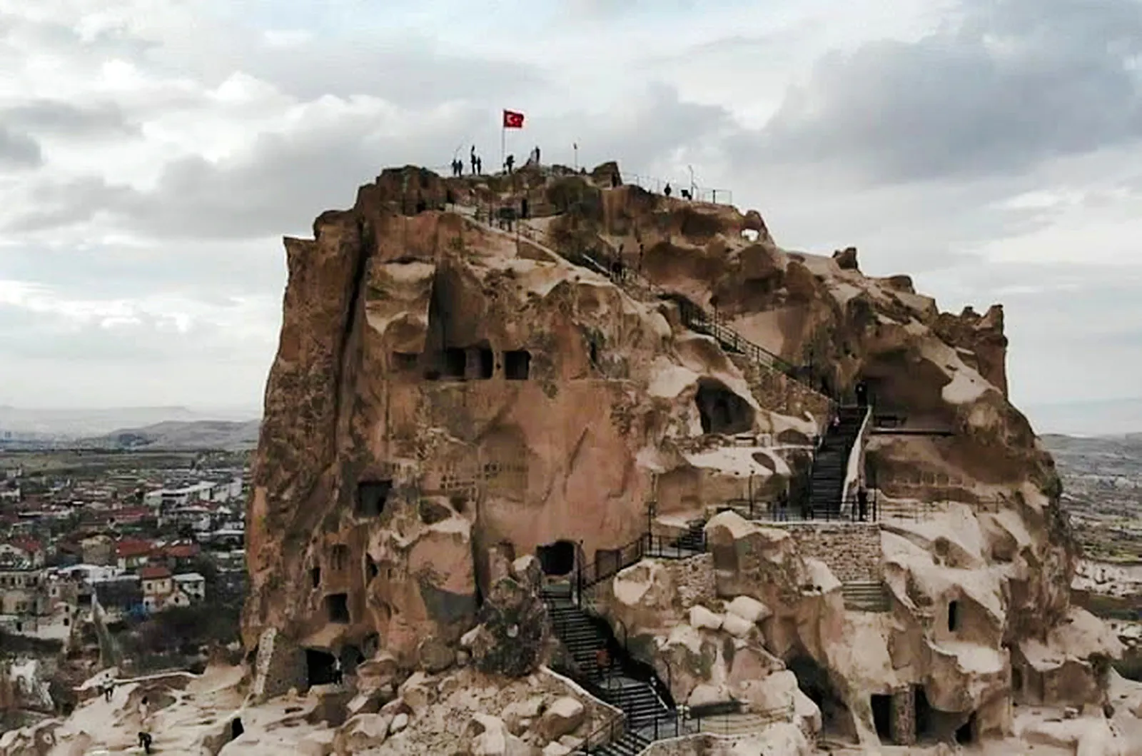 Ancient rock formations with stairs and Turkish flag in Cappadocia, part of the Red Tour.