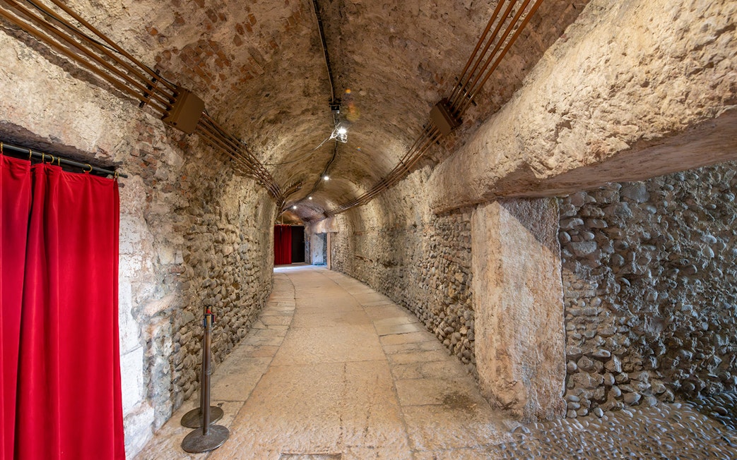 Interior hallway with stone walls and red curtains inside Verona Arena.