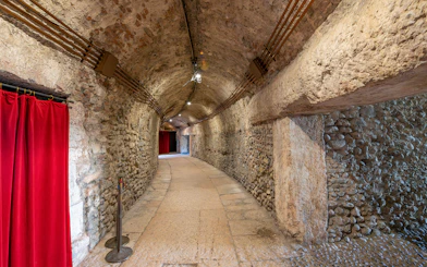 Interior hallway with stone walls and red curtains inside Verona Arena.