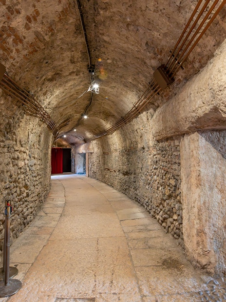 Interior hallway with stone walls and red curtains inside Verona Arena.
