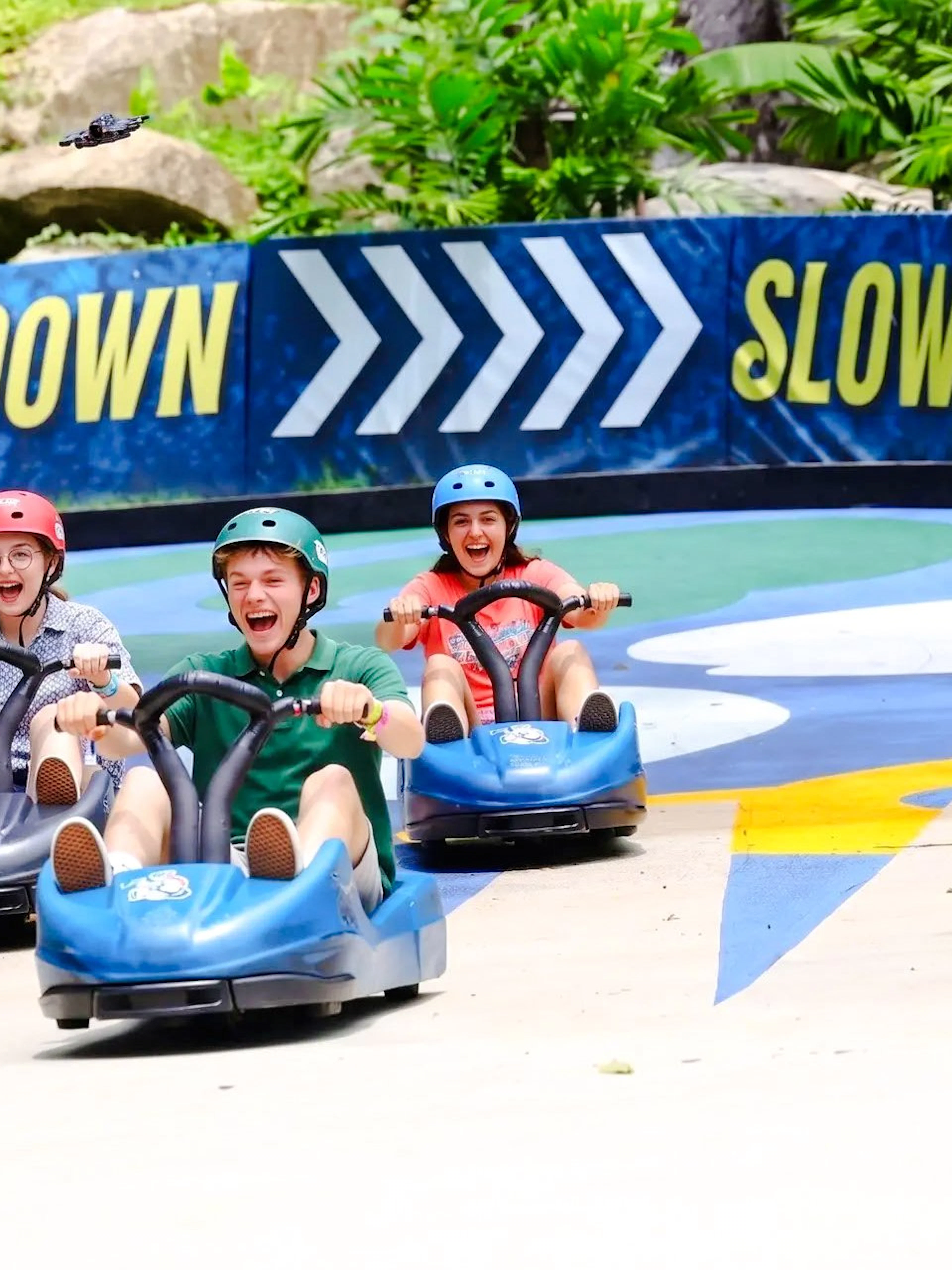Three friends enjoying a luge ride at Hanuman Luge, surrounded by greenery.