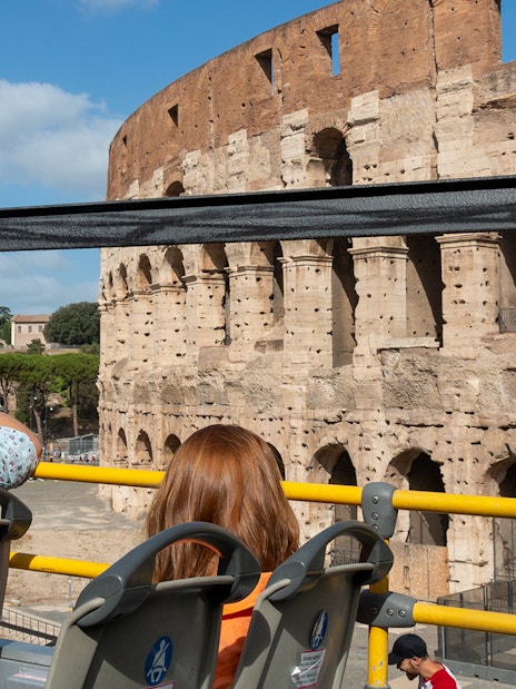 Hop-on hop-off bus near Colosseum in Rome with kids' audio guide.
