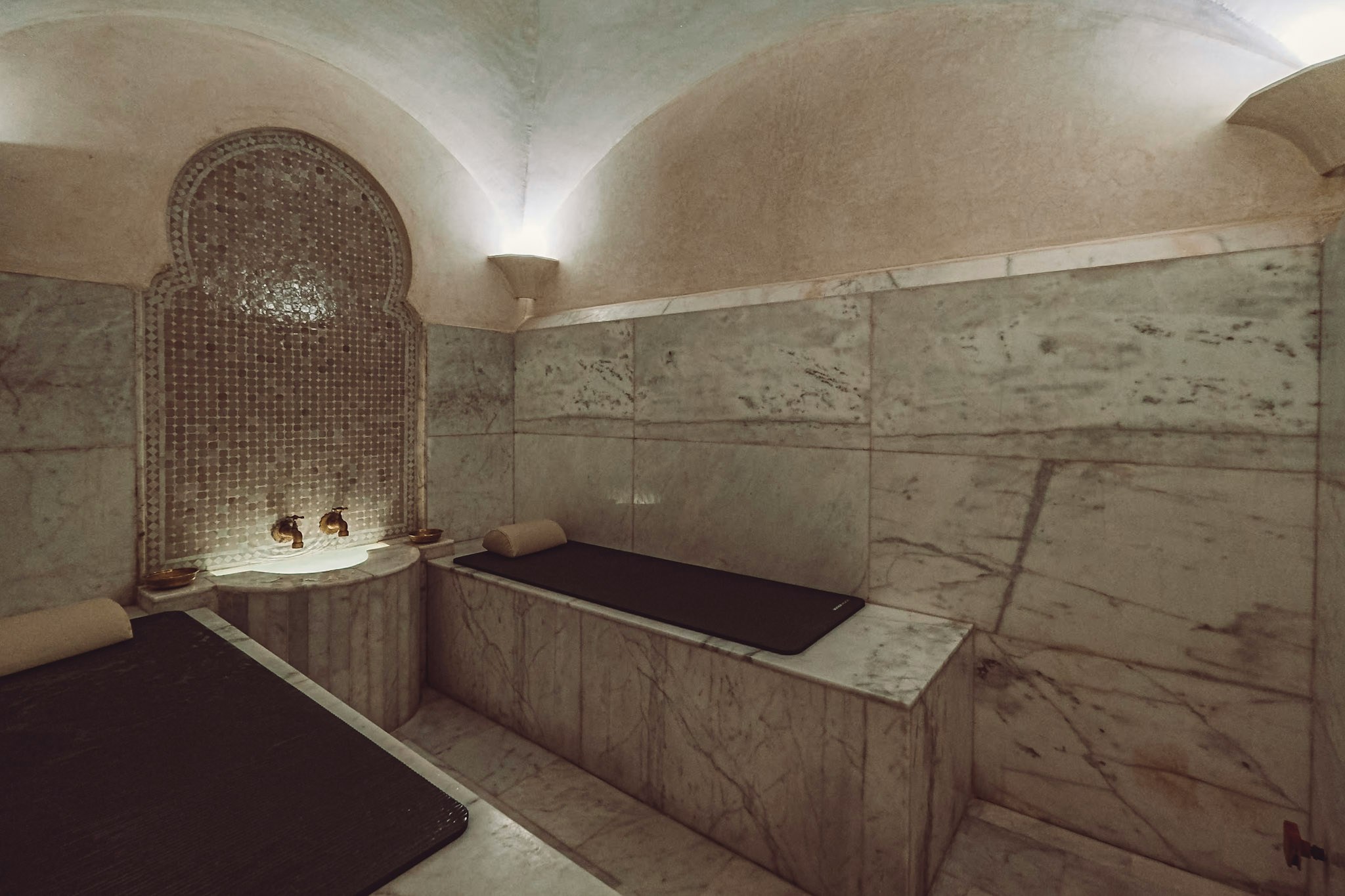Luxury steam hammam with marble benches and ornate wall design.