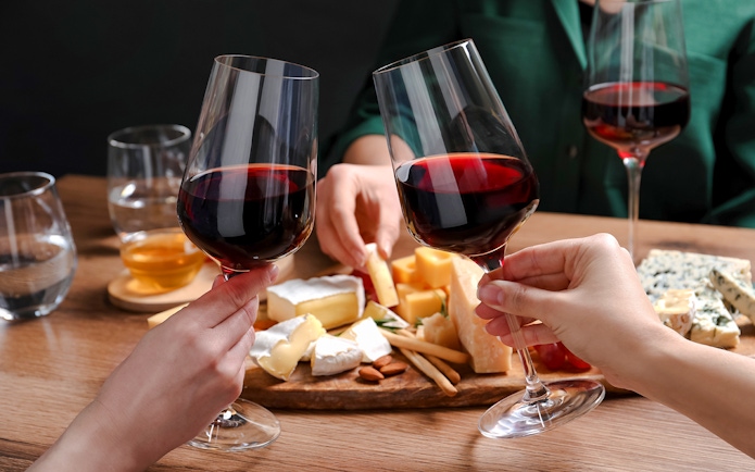 Clinking wine glasses over cheese platter at Cheese Museum in Paris.