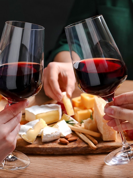 Clinking wine glasses over cheese platter at Cheese Museum in Paris.