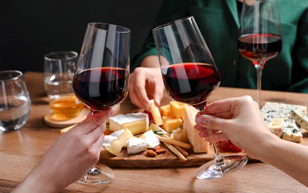 Clinking wine glasses over cheese platter at Cheese Museum in Paris.
