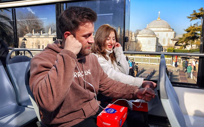 Tourists on Istanbul hop-on hop-off bus with Hagia Sophia in background.