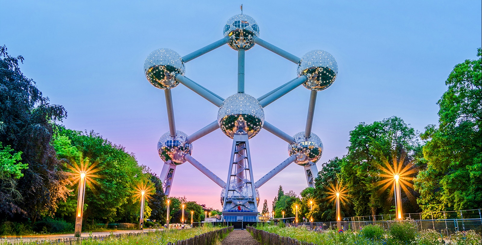 Atomium structure in Brussels surrounded by trees at dusk.