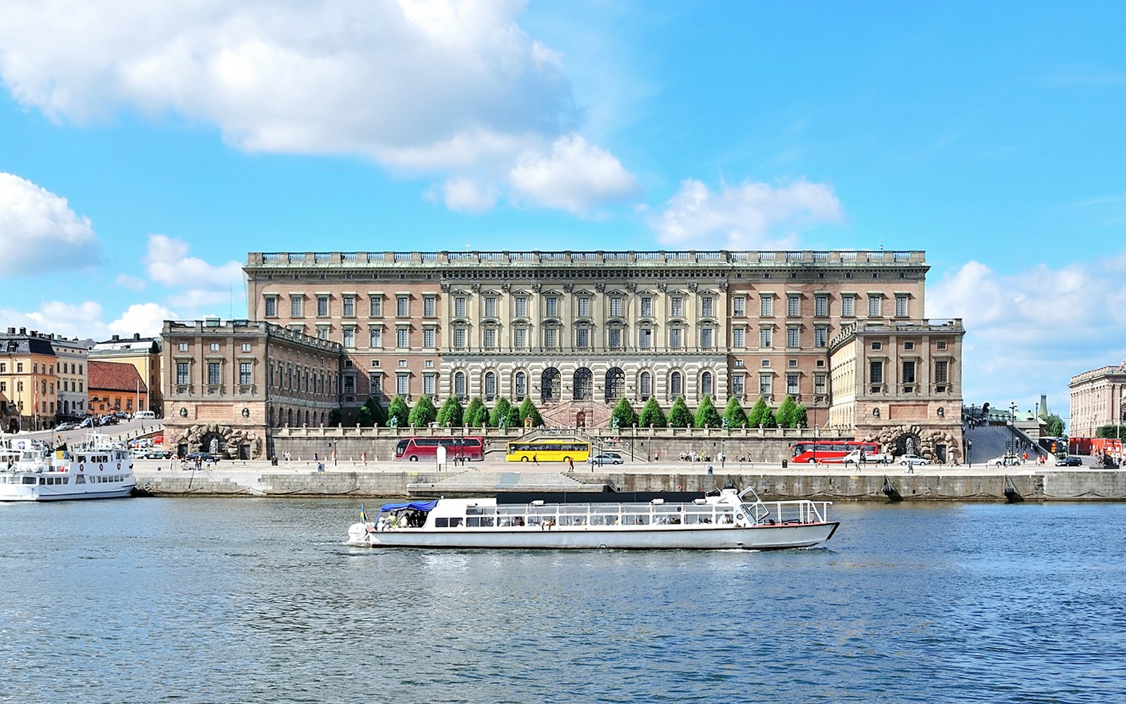 Royal Palace of Stockholm with tour boats on the water.