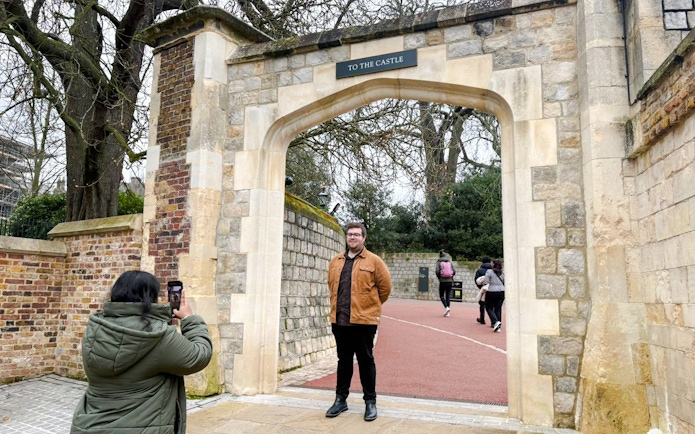 Visitors at Windsor Castle entrance, one taking a photo, others walking through the archway.