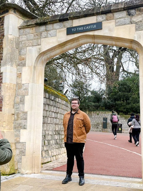 Visitors at Windsor Castle entrance, one taking a photo, others walking through the archway.