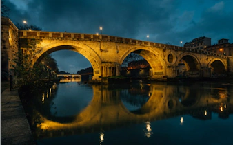 Ancient stone bridge over the Tiber River in Rome at night, part of Ghosts of Rome tour.