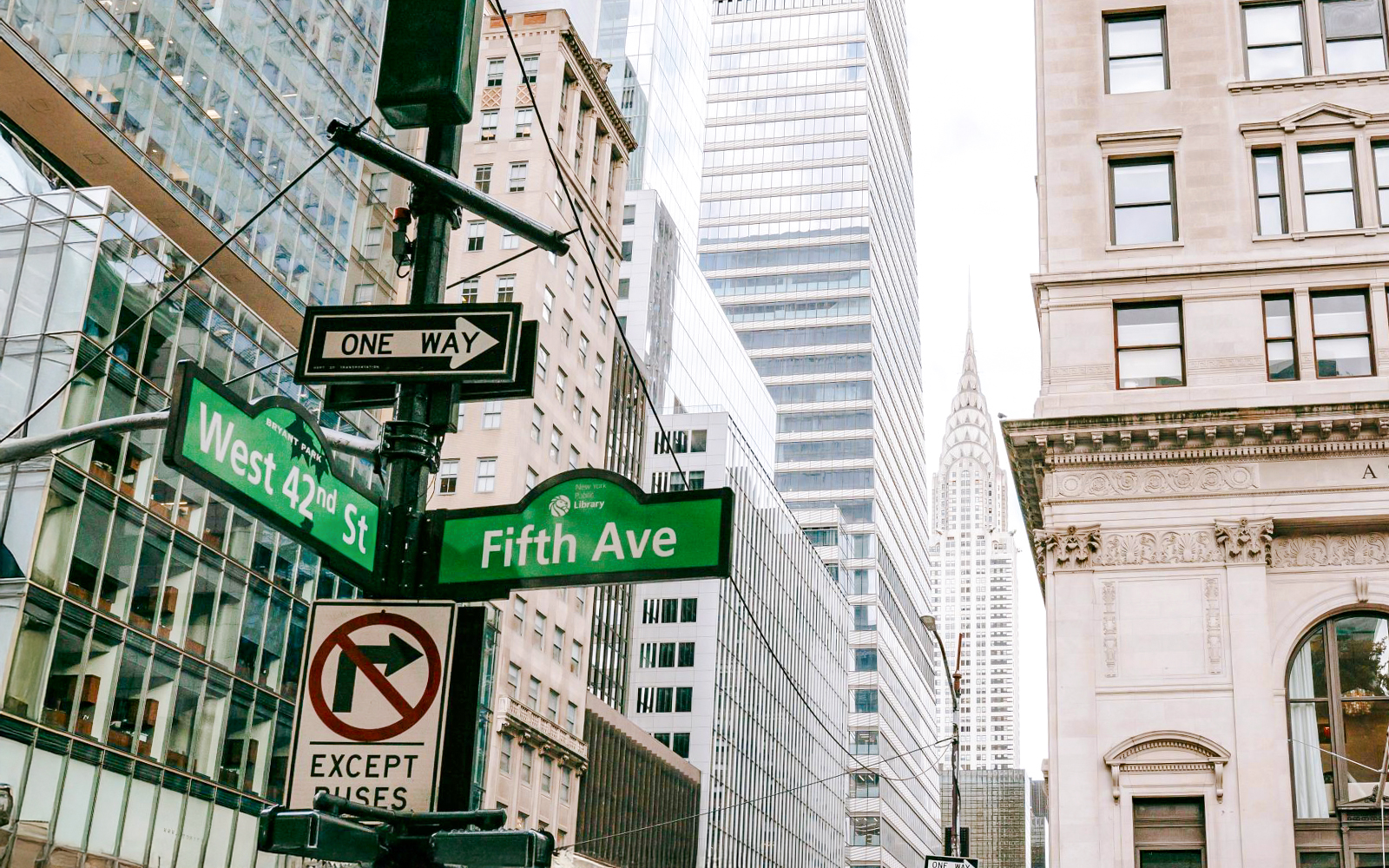 Fifth Avenue and West 42nd Street signs with skyscrapers in New York City.