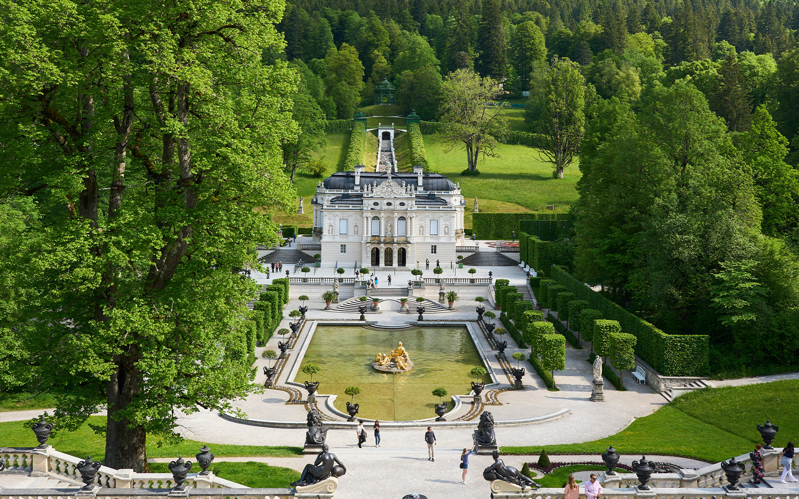Linderhof Castle in Germany with ornate gardens and fountain in foreground.