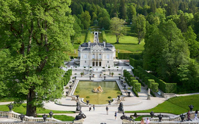 Linderhof Castle in Germany with ornate gardens and fountain in foreground.