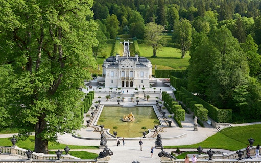 Linderhof Castle in Germany with ornate gardens and fountain in foreground.