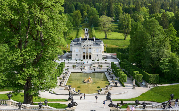 Linderhof Castle in Germany with ornate gardens and fountain in foreground.