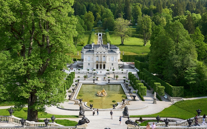 Linderhof Castle in Germany with ornate gardens and fountain in foreground.