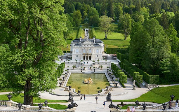 Linderhof Castle in Germany with ornate gardens and fountain in foreground.