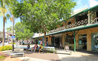 Outdoor shopping area in Darwin with people sitting and walking, part of a guided half-day city tour.