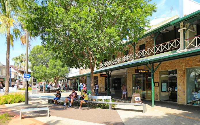 Outdoor shopping area in Darwin with people sitting and walking, part of a guided half-day city tour.