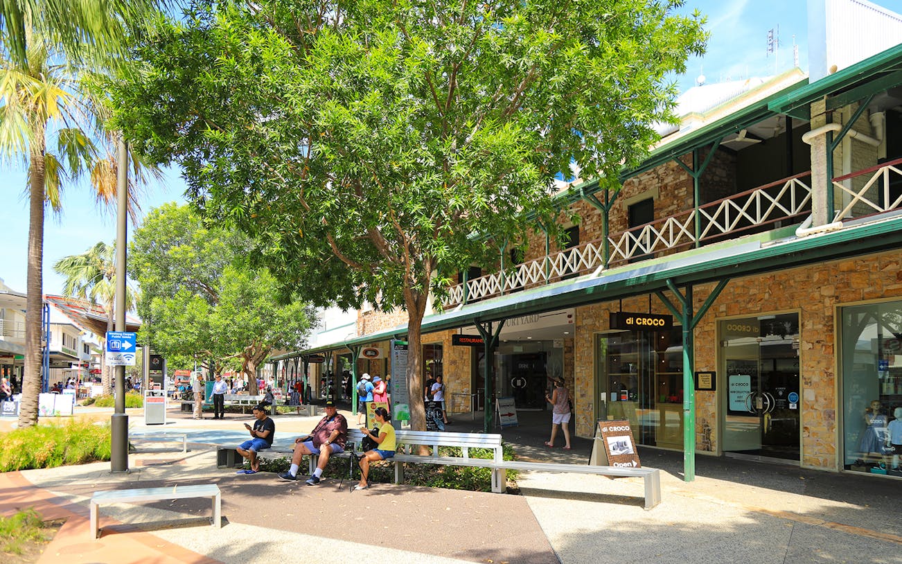 Outdoor shopping area in Darwin with people sitting and walking, part of a guided half-day city tour.