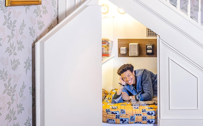 Tourist lying in Harry Potter's cupboard under the stairs set.