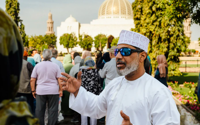 Guide explaining to tourists at Sultan Qaboos Grand Mosque, Oman.