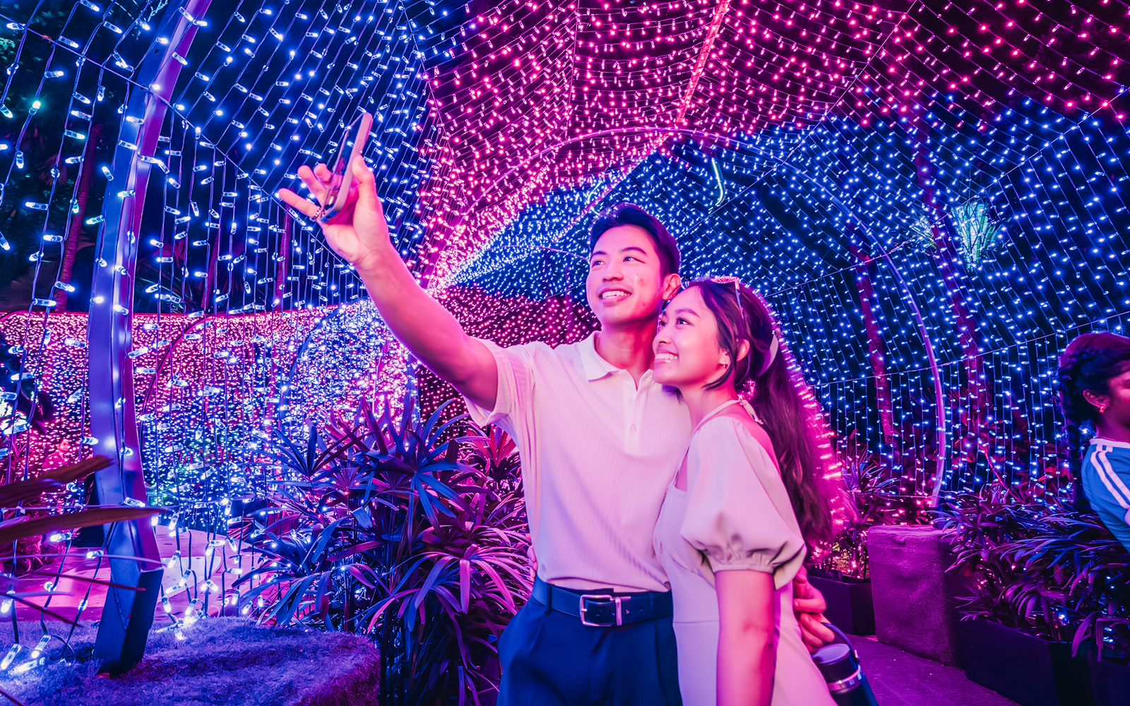 Couple taking a selfie under colorful Christmas lights at Gardens by the Bay.