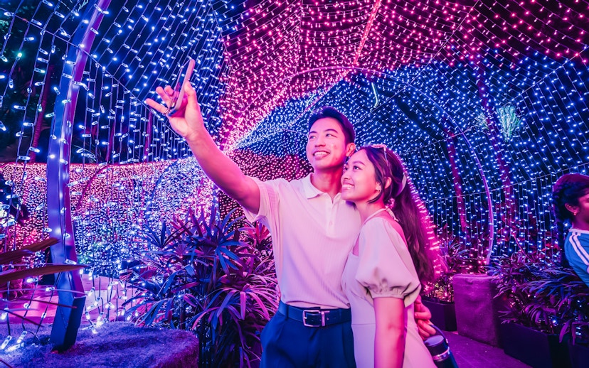 Couple taking a selfie under colorful Christmas lights at Gardens by the Bay.