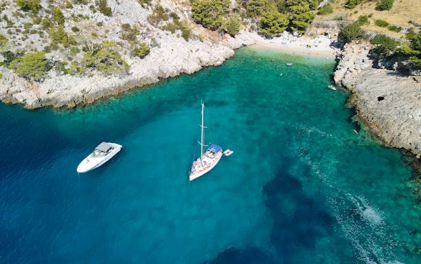 Sailing yacht near rocky coastline and beach on Hvar and Pakleni Islands.