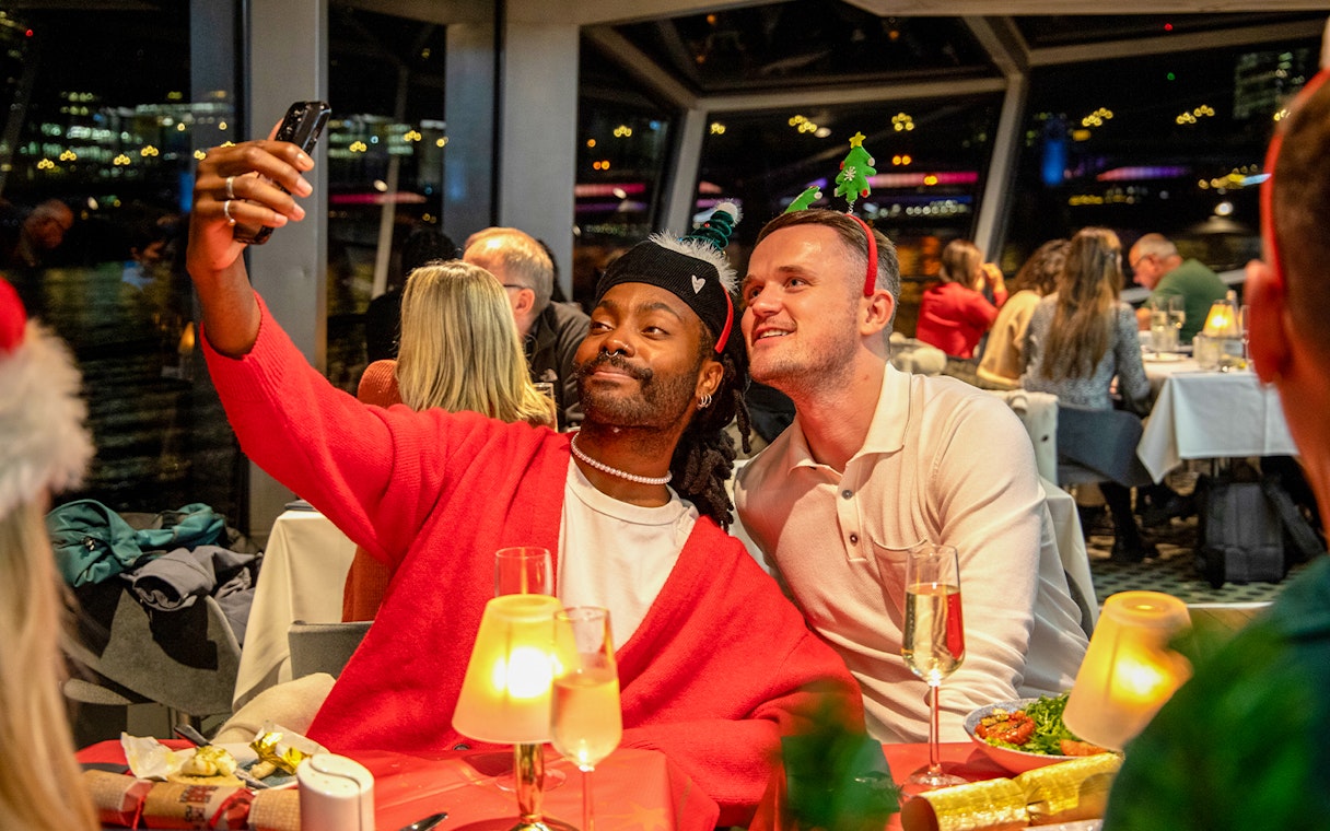 Guests taking a selfie at a Christmas dinner party on a Thames River cruise.