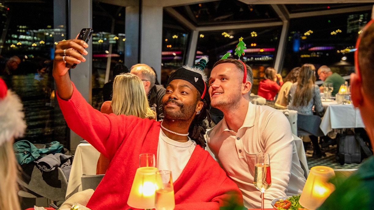 Guests taking a selfie at a Christmas dinner party on a Thames River cruise.