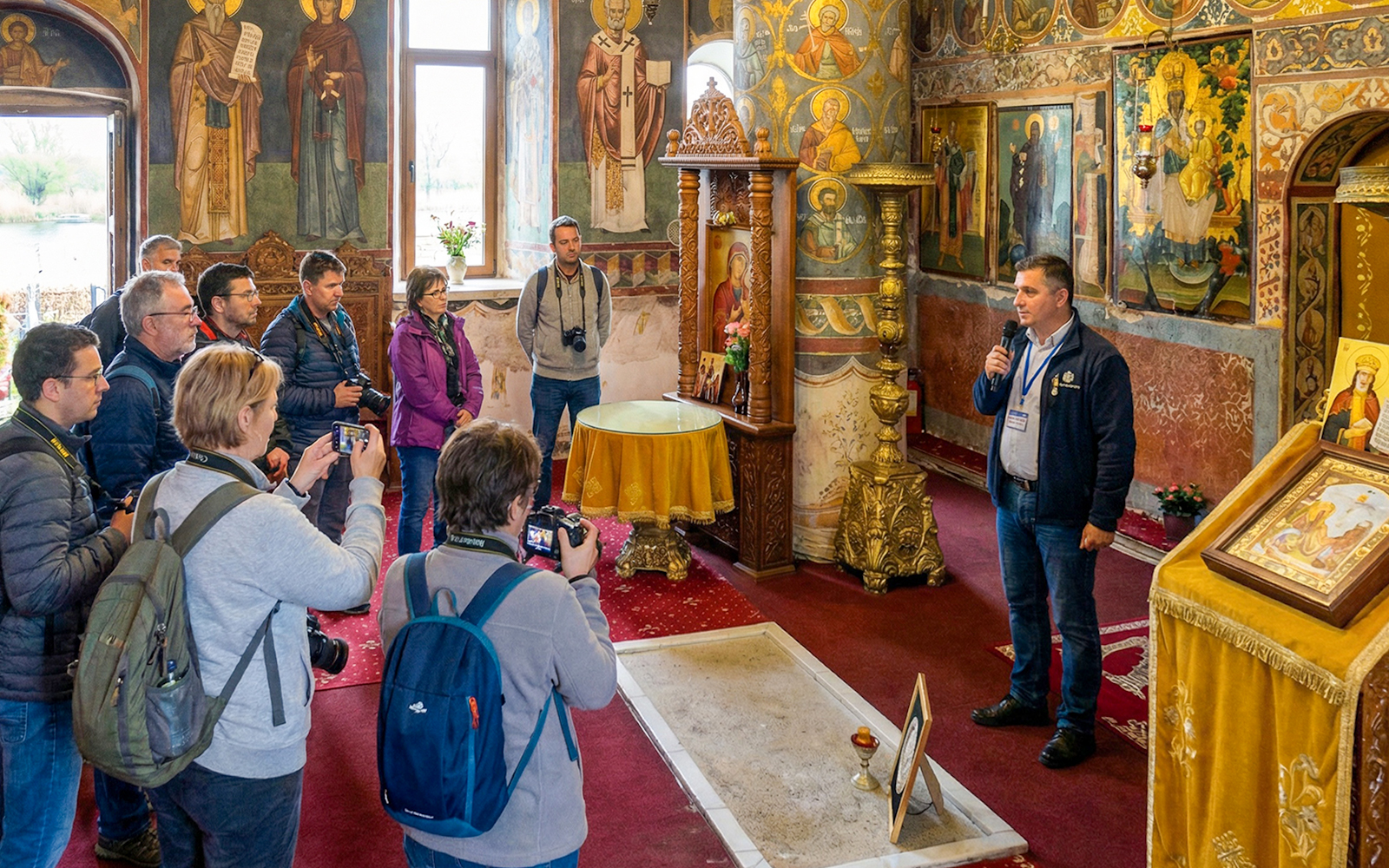 Tour guide explaining Dracula's Tomb inside Snagov Monastery to a group of visitors.