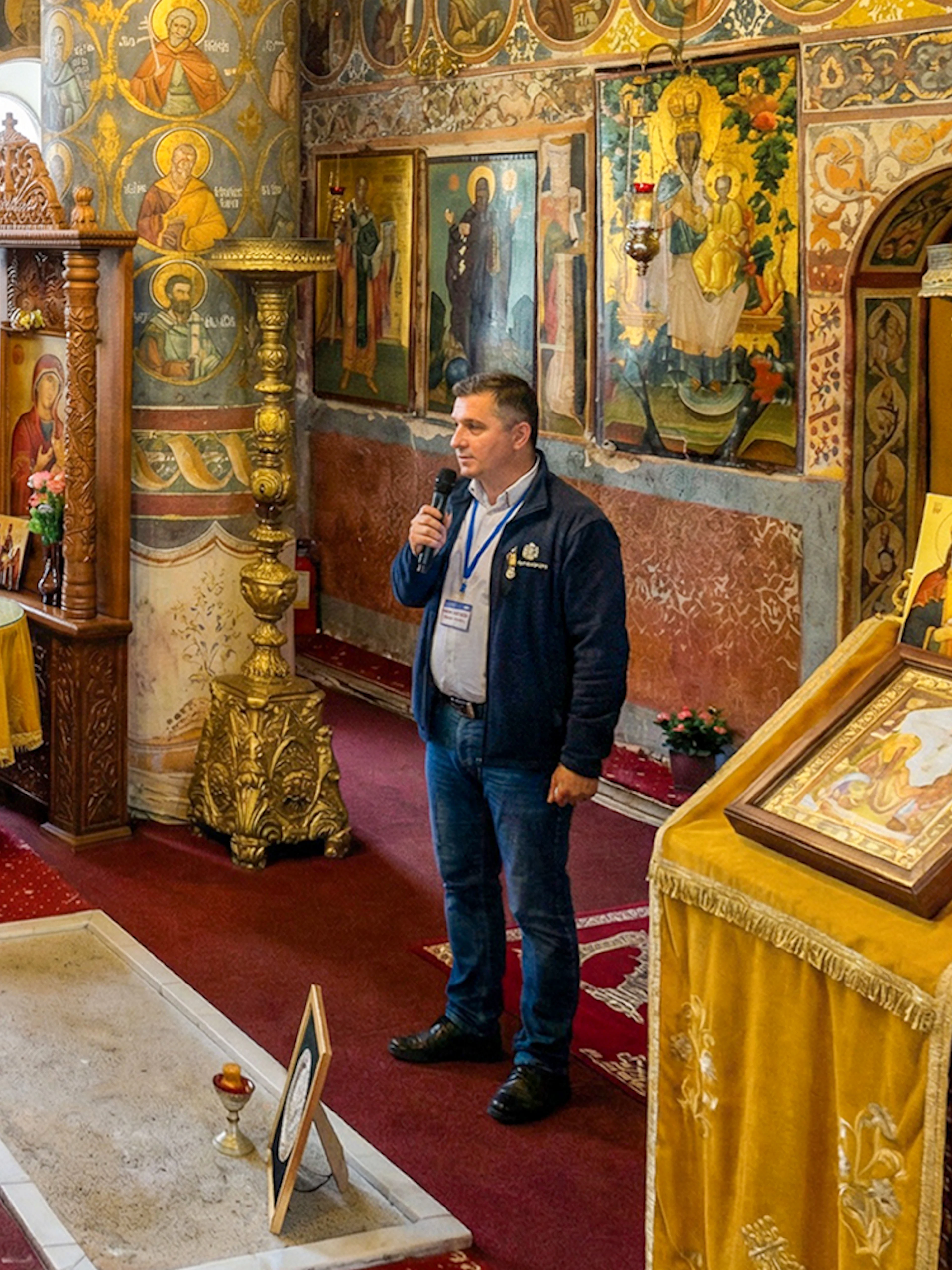 Tour guide explaining Dracula's Tomb inside Snagov Monastery to a group of visitors.