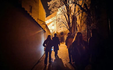 Night tour group walking through Old Town Prague alley.