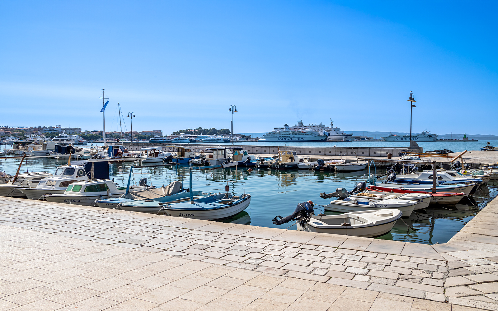 Boats docked at Matejuška Pier in Split, Croatia, with Adriatic Sea in the background.