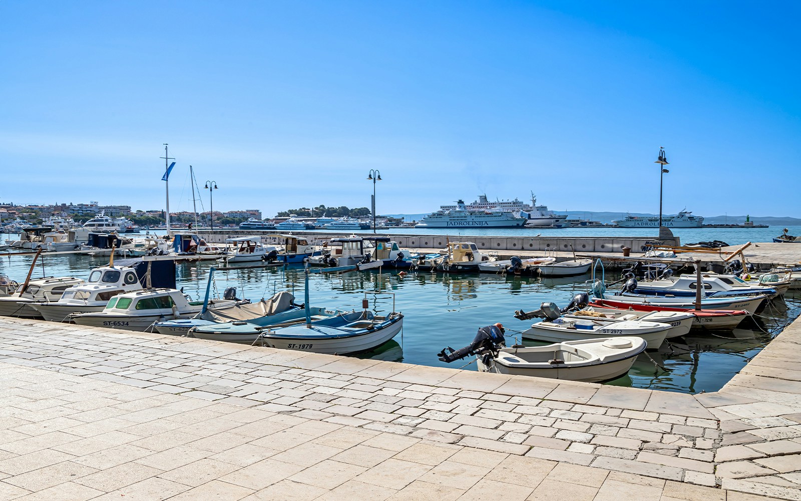 Boats docked at Matejuška Pier in Split, Croatia, with Adriatic Sea in the background.
