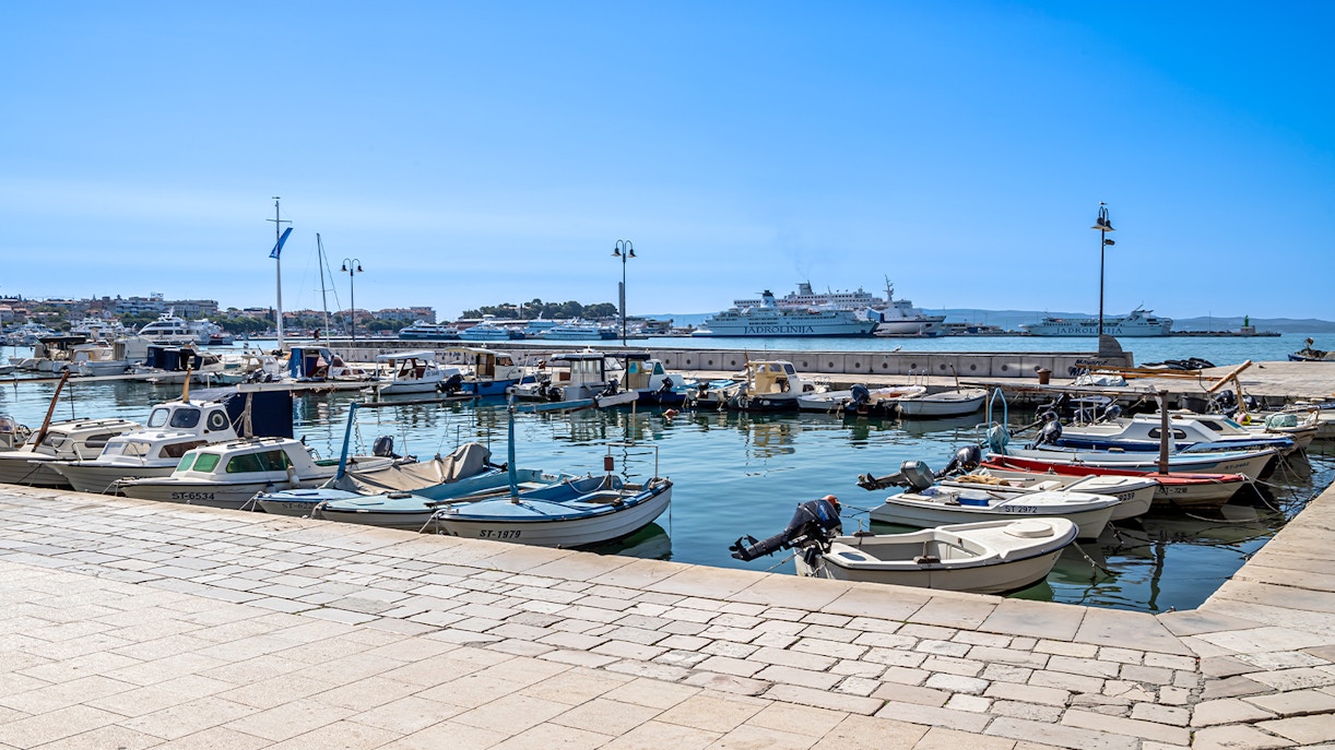 Boats docked at Matejuška Pier in Split, Croatia, with Adriatic Sea in the background.