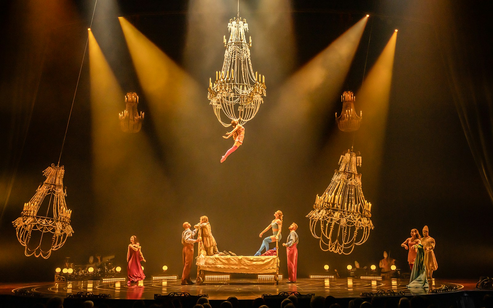 Acrobats perform on a bed under chandeliers in Cirque du Soleil's Corteo show.