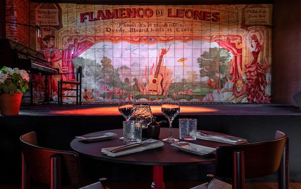 Flamenco De Leones stage with guitar mural and dining setup in Madrid.