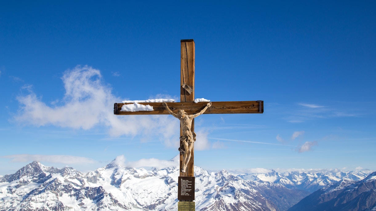 Crucifix at Matterhorn Glacier Paradise with snow-covered Alps in the background.