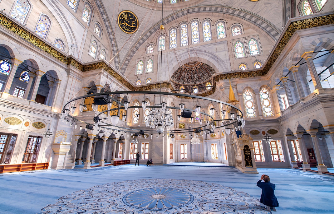 Interior view of Blue Mosque in Istanbul with intricate tilework and ornate chandeliers.