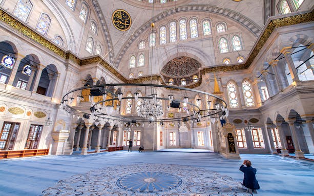 Interior of the Blue Mosque in Istanbul with ornate chandeliers and stained glass windows.