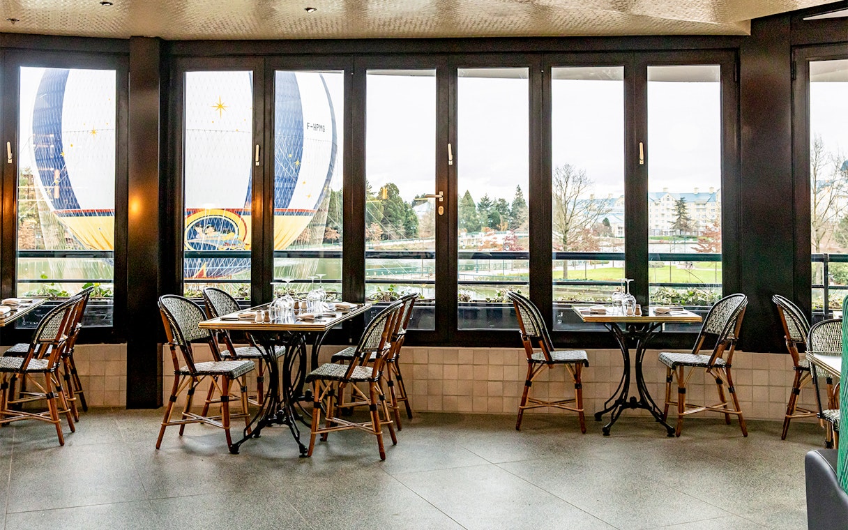 Dining tables at La Flottille with a view of a hot air balloon outside.