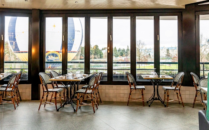 Dining tables at La Flottille with a view of a hot air balloon outside.