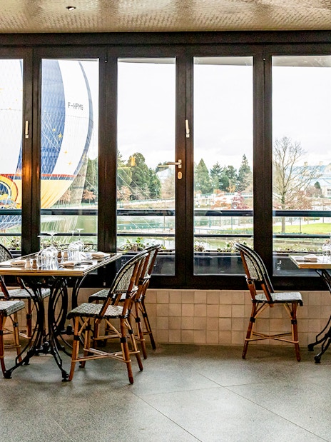 Dining tables at La Flottille with a view of a hot air balloon outside.