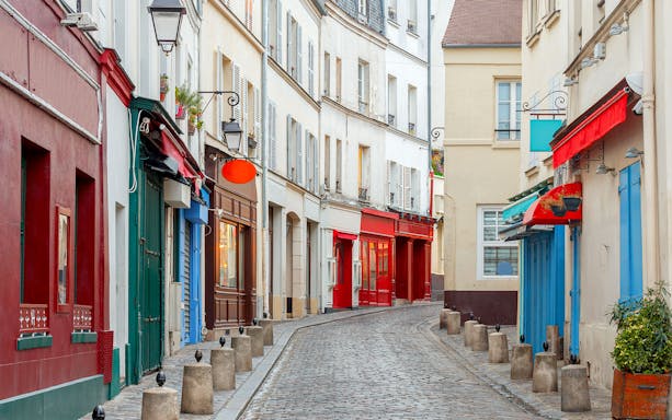 Cobblestone street with colorful storefronts in Paris, part of a guided food tour.